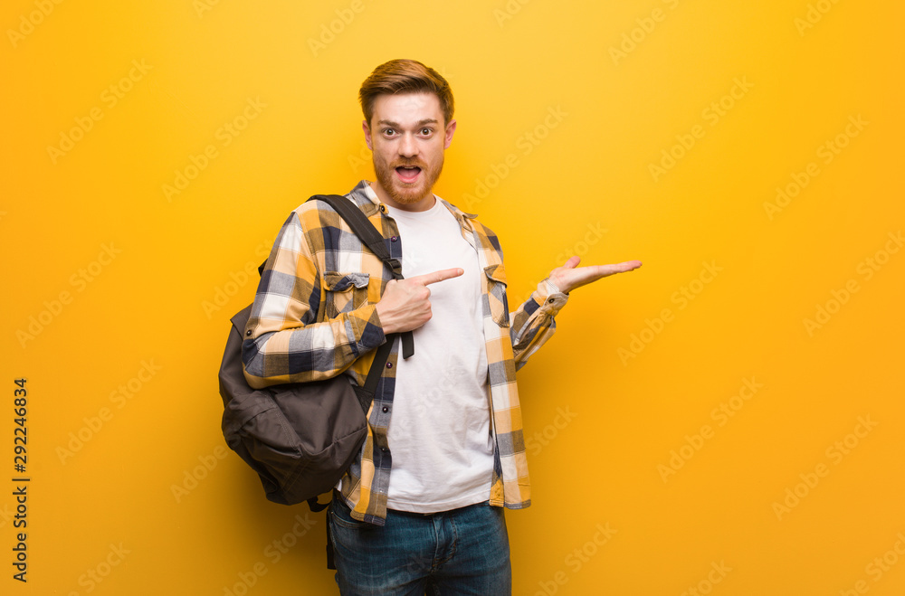 Young redhead student man holding something with hand Young redhead student man holding something with hand