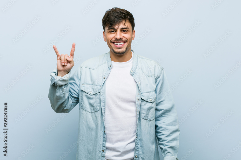 Young hispanic cool man showing a horns gesture as a revolution concept. Young hispanic cool man showing a horns gesture as a revolution concept.