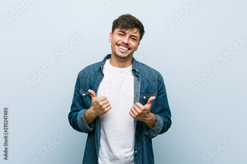 Young hispanic cool man raising both thumbs up, smiling and confident.