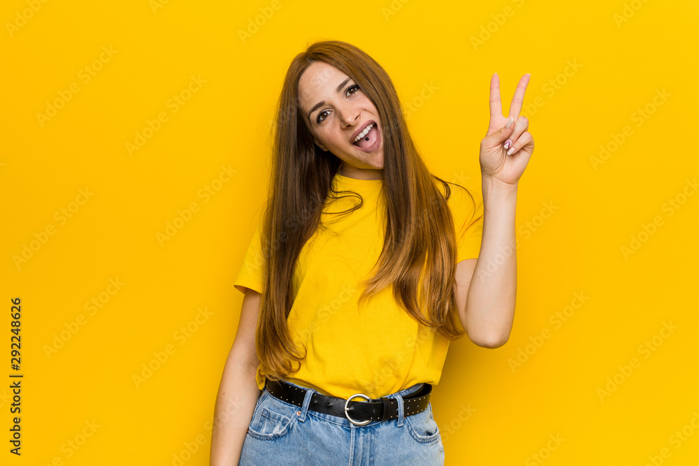 Young ginger redhead woman joyful and carefree showing a peace symbol with fingers. Young ginger redhead woman joyful and carefree showing a peace symbol with fingers.