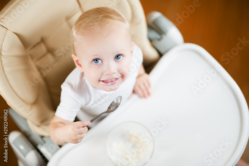 baby girl eats porridge and looks up, smiling joyfully