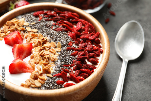 Smoothie bowl with goji berries and spoon on grey table, closeup