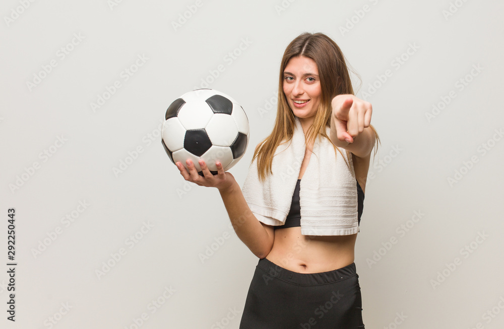 Young fitness russian woman cheerful and smiling. Holding a soccer ball.