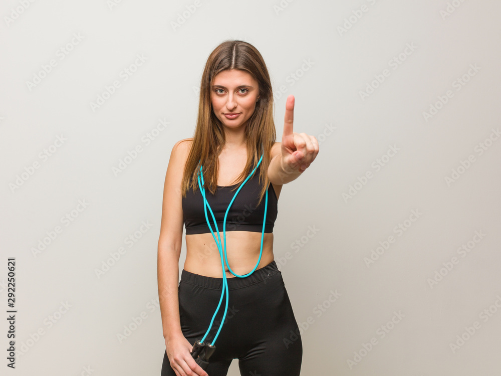 Young fitness russian woman showing number one. Holding a jump rope. Young fitness russian woman showing number one. Holding a jump rope.
