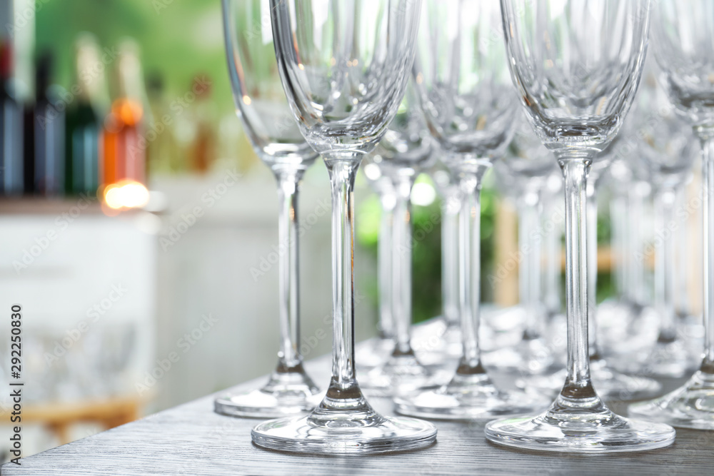 Empty glasses on wooden table against blurred background, closeup view Empty glasses on wooden table against blurred background, closeup view