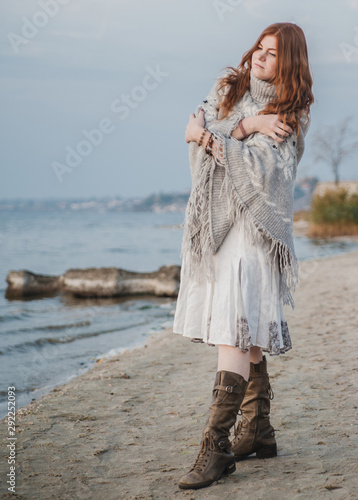 Close up portrait of beautiful redhead woman in poncho posing outdoors.