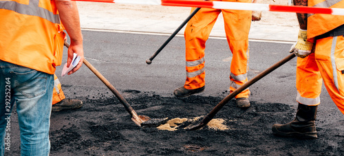 Group of people workers wearing special protection and safety orange costumes posing asphalt in Dutch city central square street