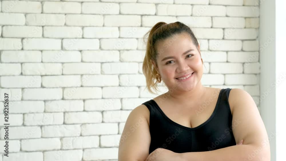 Plus size girl stand and smile in front of camera that look confidence in the room with day light. Plus size girl stand and smile in front of camera that look confidence in the room with day light.