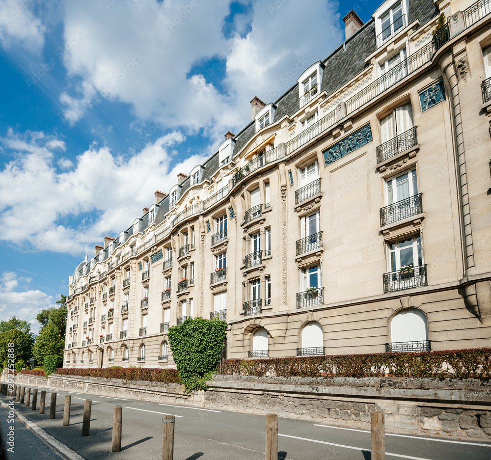 View of Parisian luxury property apartment building with French balconies and clear blue sky with some scattered clouds