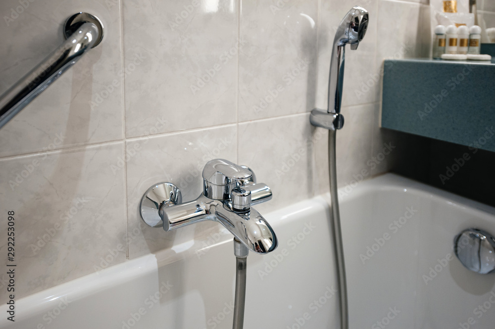 View of modern bathroom with bathtub detail and chrome water shower tap View of modern bathroom with bathtub detail and chrome water shower tap
