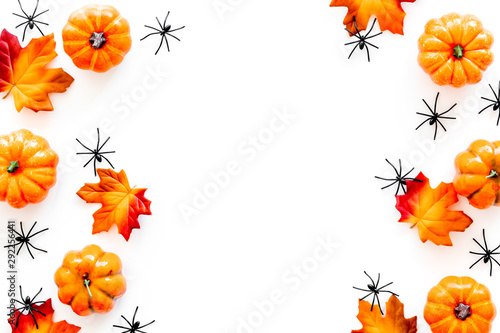 Nice halloween frame. Small spiders among leaves and pumpkins on white top view copy space