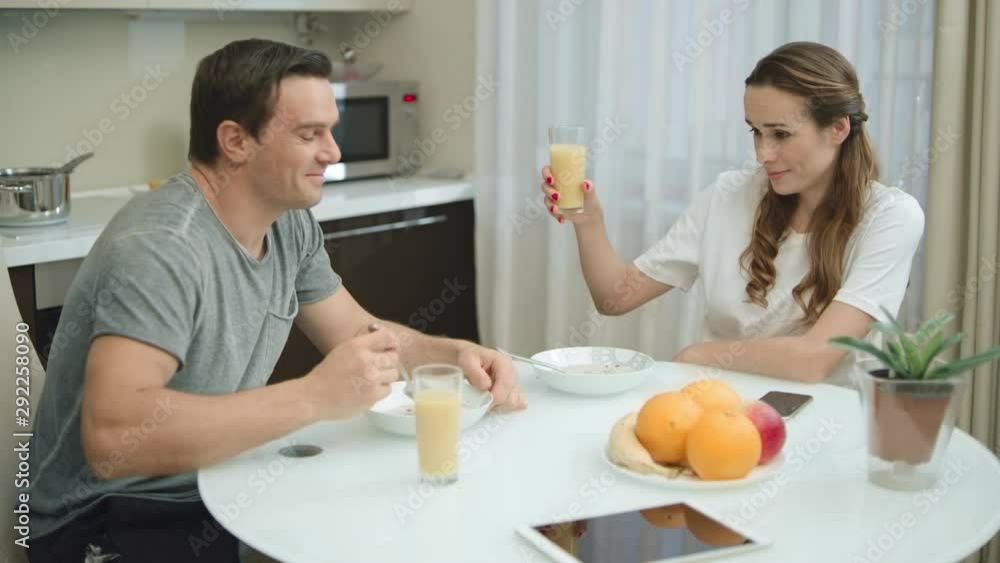 Cheerful couple making cheers with orange juice. Cheerful couple making cheers with orange juice.