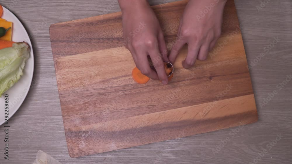 Using flower shaped mold to cut decoration out of fresh raw carrot. Top view Using flower shaped mold to cut decoration out of fresh raw carrot. Top view