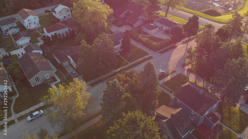 Fototapeta premium Aerial view of residential houses at summer. American neighborhood, suburb. Real estate, drone shots, sunset, sunlight, from above.