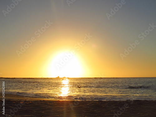 Fototapeta Naklejka Na Ścianę i Meble -  A beautiful sunset with the sun approaching the horizon at the sea seen from the beach of Algarrobo, Chili