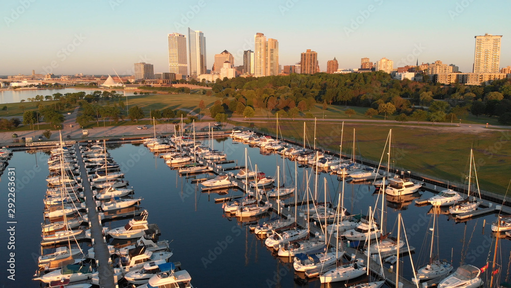 Obraz premium Aerial view of american city at dawn. High-rise buildings, sailing yachts, boat dock. Sunny morning, summer. Milwaukee, Wisconsin, United States