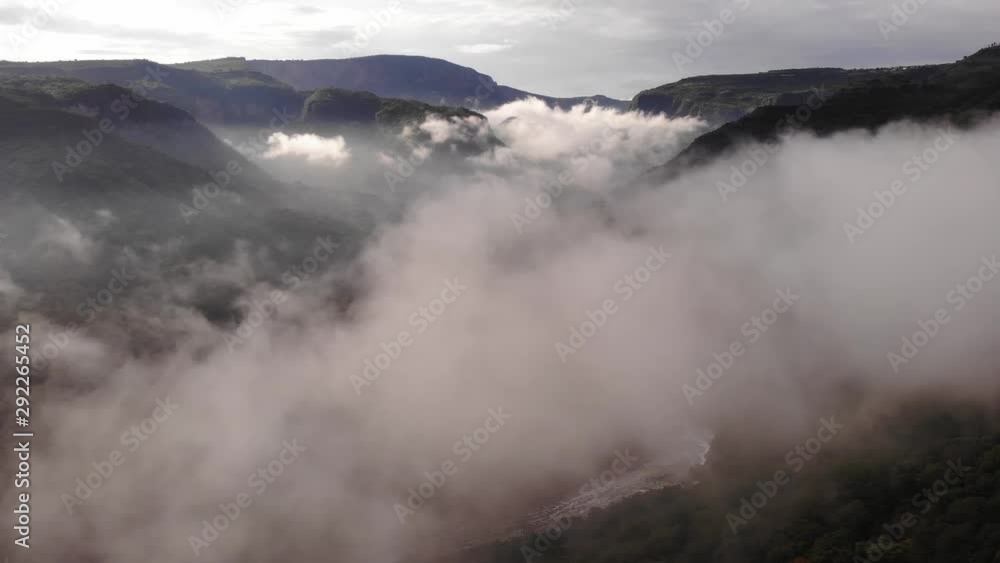 Flight over canyon with a river passing through the clouds Flight over canyon with a river passing through the clouds