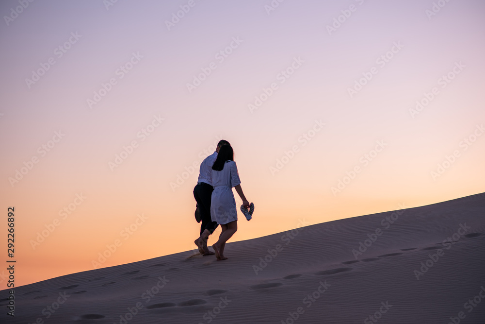 Couple walking on sand dune during golden hour Couple walking on sand dune during golden hour