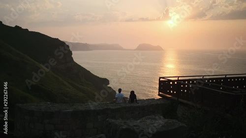 Two people on a ridge, watching the sunset. photo