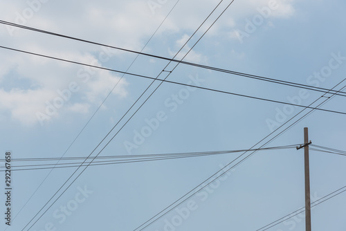 Closeup of a cement pole and neat wires network in blue sky background © bqmeng