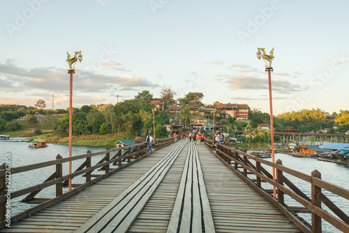 Kanchanaburi / Thailand- March 22 2019 local Mon people and tourists walk on vintage wooden bridge across river © jummie