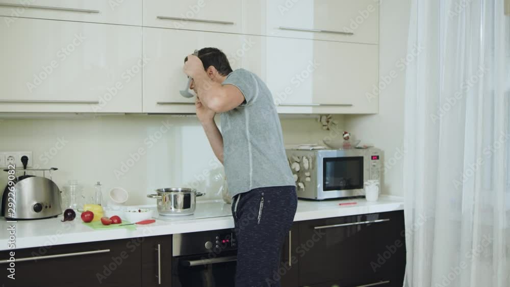 Happy man cooking healthy dinner at home. Cheerful husband talking phone Happy man cooking healthy dinner at home. Cheerful husband talking phone