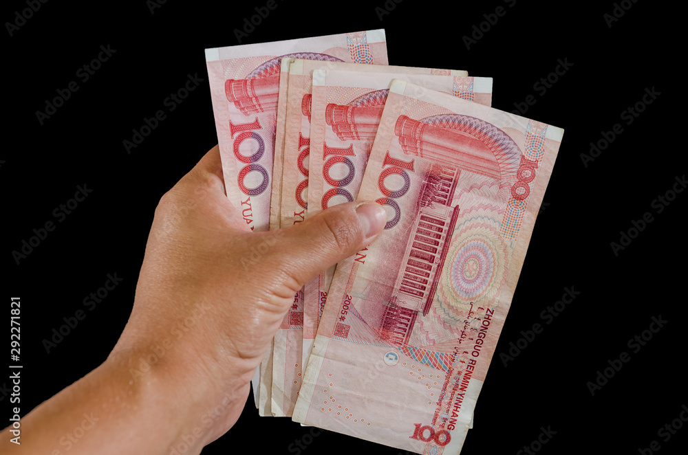 Chinese money in hand on a black background. Yuan close up.