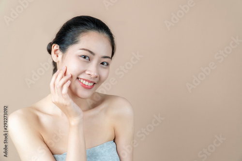 Asian woman smiling and touching her face. Skincare and Cosmetology concept. beige background
