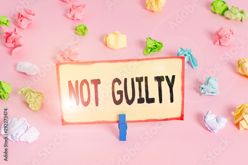 Conceptual hand writing showing Not Guilty. Concept meaning someone is innocent didnt commit specific crime He free Colored crumpled papers empty reminder pink floor clothespin