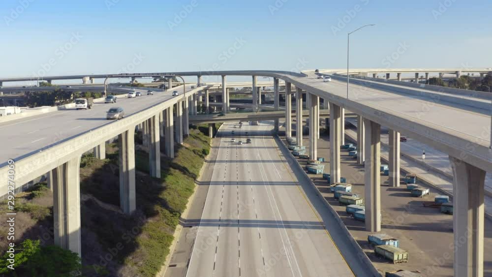 4K. Aerial. Los Angeles freeway. Drone camera moves slowly in between the overpass supports over the roadbed with cars driving the way towards the drone. Many road intersections are seen. 4K. Aerial. Los Angeles freeway. Drone camera moves slowly in between the overpass supports over the roadbed with cars driving the way towards the drone. Many road intersections are seen.