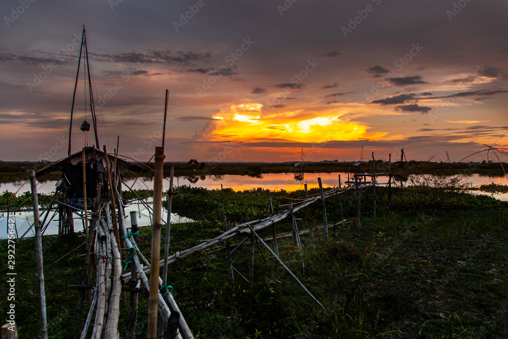 Traditional fishing tool or bamboo fish trap on sunset light, landscape silhouette.