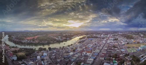 Aerial view panorama above Ban Pong City and Mae Klong river evening with yellow sun light and cloudy sky background, sunset with soft rain in Ban Pong City, Ratchaburi, Thailand.