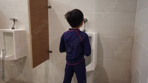 the boy peeing to toilet bowl in restroom photo