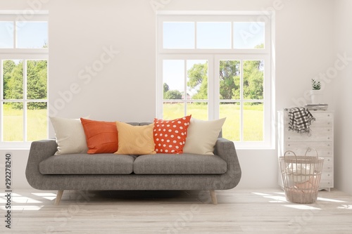 Stylish room in white color with sofa and summer landscape in window. Scandinavian interior design. 3D illustration