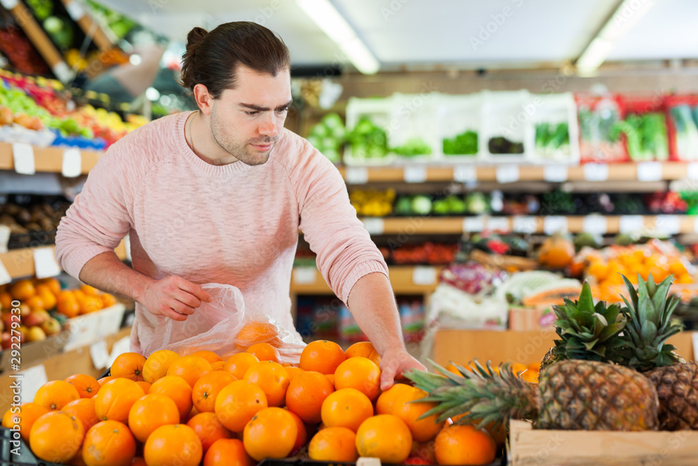 Man customer choosing fresh oranges  on the supermarket