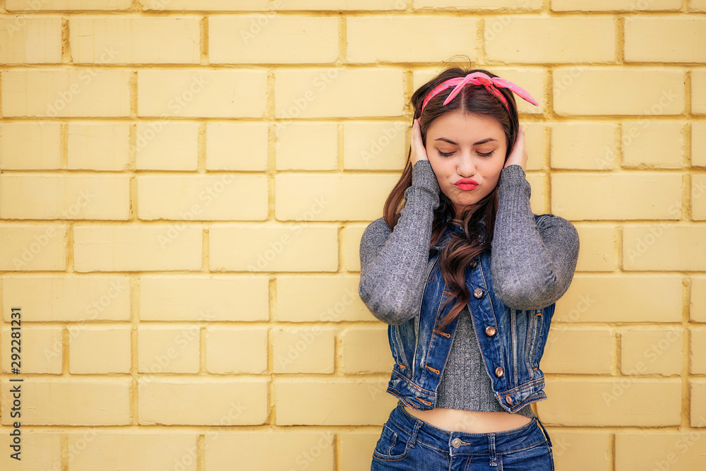 young woman in a denim suit with a pink bow emotionally fun posing on a background of a yellow brick wall. copy space young woman in a denim suit with a pink bow emotionally fun posing on a background of a yellow brick wall. copy space