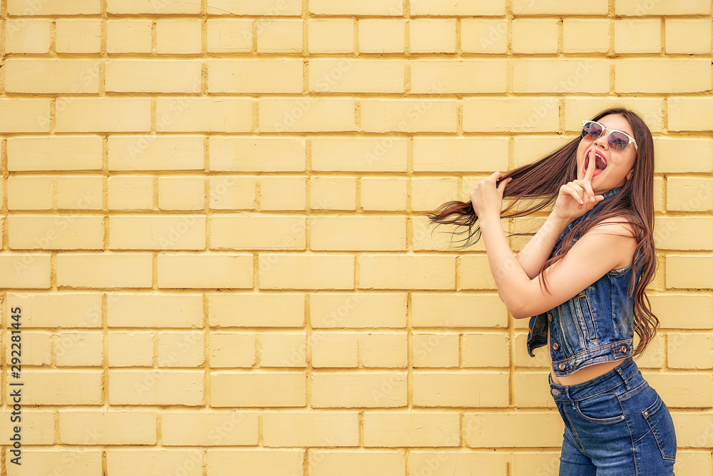 crazy girl emotionally posing on a background of yellow brick wall. copy space