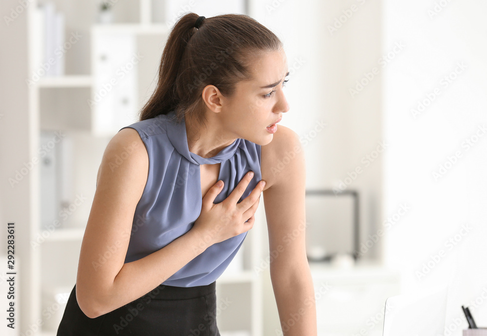 Young woman suffering from heart attack in office