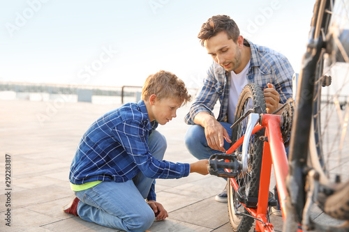 Father and his son repairing bicycle outdoors