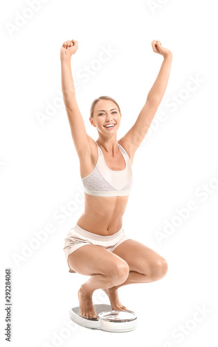 Happy young woman on scales against white background. Weight loss concept