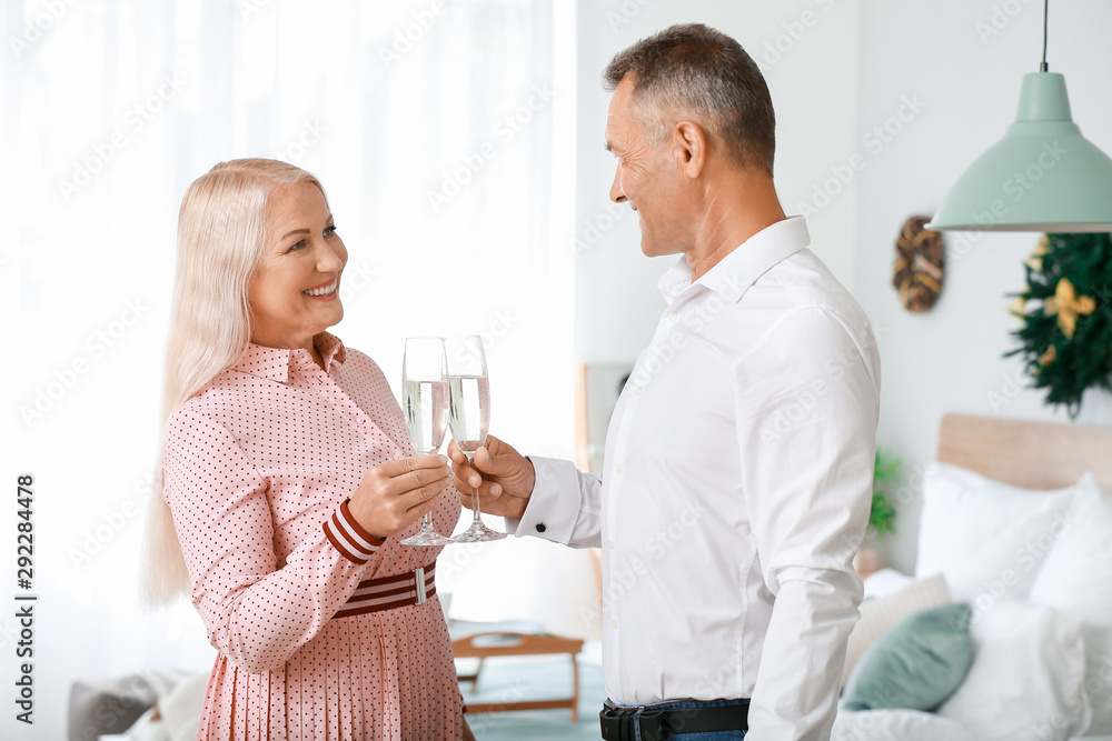 Obraz premium Mature couple with glasses of champagne celebrating Christmas at home