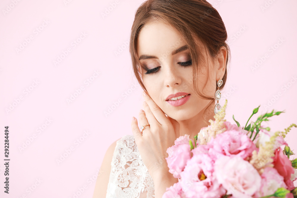 Portrait of beautiful young bride with wedding bouquet on color background