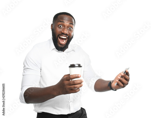 Excited African-American businessman with cup of coffee and mobile phone on white background © Pixel-Shot