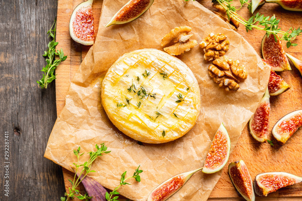 Baked camembert cheese with figs, walnuts, honey and thyme on the rustc background. Selective focus. Shallow depth of field. Baked camembert cheese with figs, walnuts, honey and thyme on the rustc background. Selective focus. Shallow depth of field.