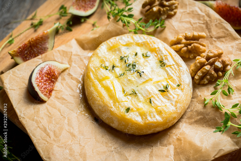 Baked camembert cheese with figs, walnuts, honey and thyme on the rustc background. Selective focus. Shallow depth of field. Baked camembert cheese with figs, walnuts, honey and thyme on the rustc background. Selective focus. Shallow depth of field.