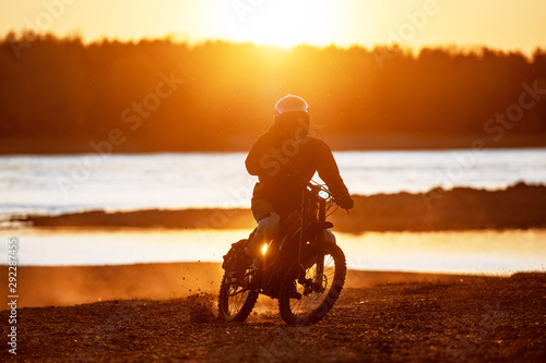 Motorcyclist on electric enduro motorbike in sunset light