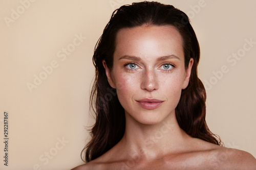 Beauty woman portrait. Beautiful spa model girl with perfect fresh clean skin. Youth and skin care concept. Beige background. Nude makeup photo