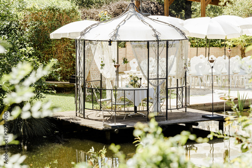 Beautifully decorated wedding ceremony location under a large oak tree, wide view.