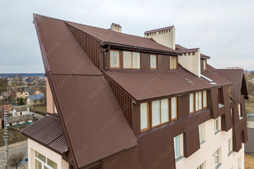 Roof of a house made from metal sheets with attic windows.