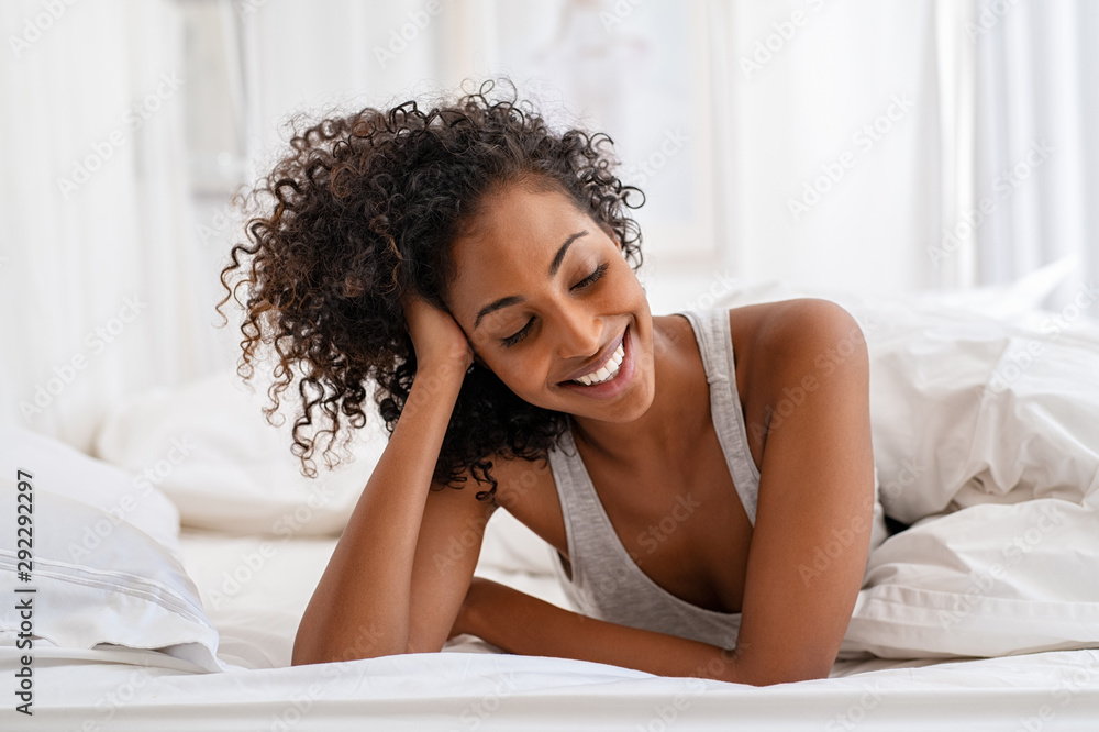 Smiling young woman lying on bed Smiling young woman lying on bed